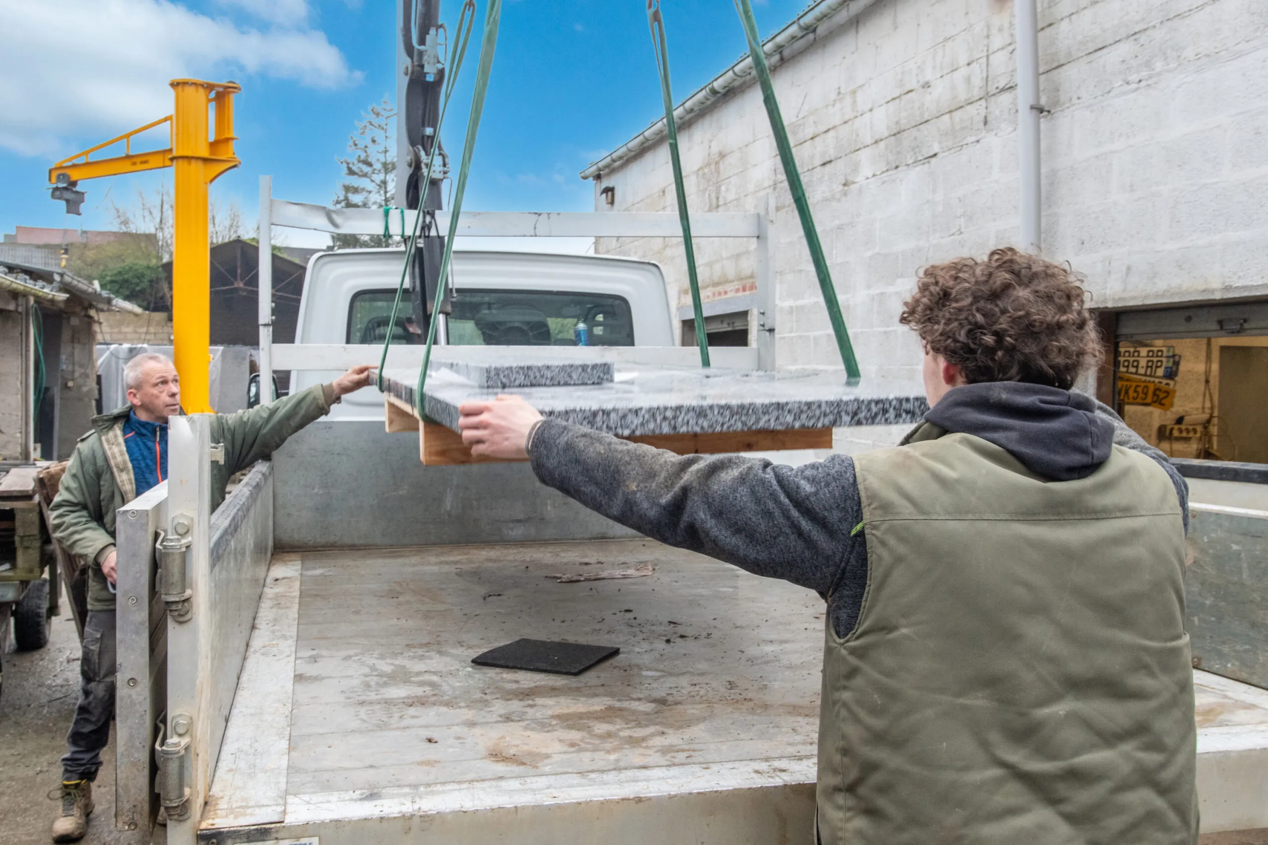 Marbrerie Dechamps Frères déchargeant une pierre tombale en granit sur un camion de livraison